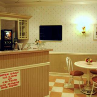 A retro-style diner interior featuring a counter, beverage machine, and seating area.