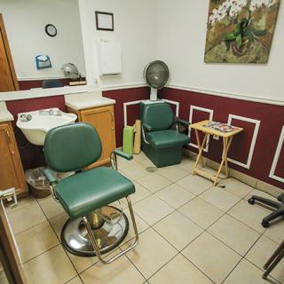 A cozy barbershop interior featuring chairs, a sink, and a mirror.