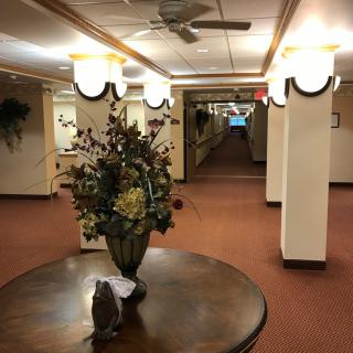 A well-lit hallway with a decorative flower arrangement on a round table.