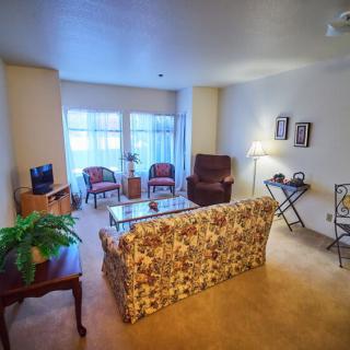 A cozy living room with a floral sofa, two chairs, a coffee table, and decorative elements.