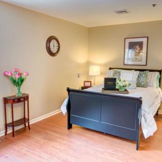 A cozy bedroom with a dark bed frame, floral decor, and a side table with flowers.
