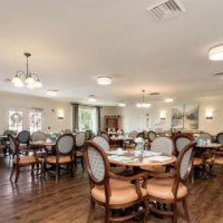 A well-lit dining room with elegant tables and chairs, featuring wooden flooring and tasteful decor.