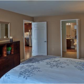 A cozy bedroom with a neatly made bed and adjacent open doors leading to other rooms.