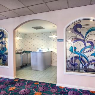A vibrant laundry room with a colorful carpet and decorative stained glass panels.