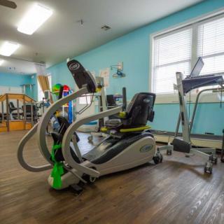A bright room filled with various exercise equipment for fitness and rehabilitation.