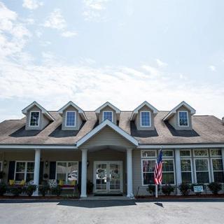 A residential-style building with a prominent entrance, featuring multiple dormer windows and an American flag displayed at the front.