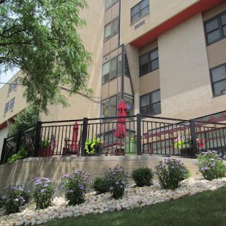 An apartment building featuring well-maintained landscaping and outdoor seating.