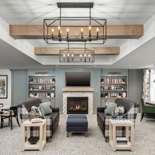 A cozy living room with elegant chandeliers, a fireplace, and built-in bookcases.