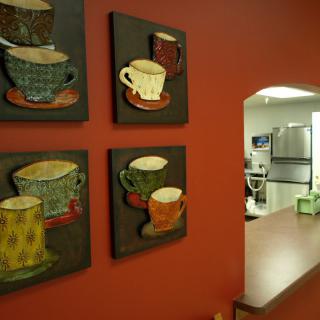 A cozy kitchen adorned with colorful coffee cup art on a warm red wall.