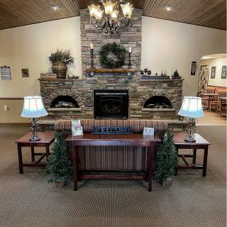 A cozy lounge area with a stone fireplace, flanked by tables and lamps, and decorated with plants.