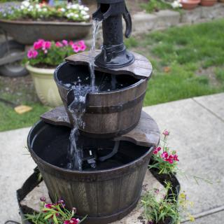 A decorative garden fountain with cascading water and surrounding flowers.