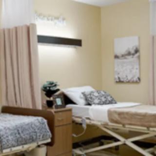 A hospital room with medical beds and curtains for privacy.
