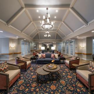A spacious lobby area featuring elegant furniture, a chandelier, and decorative carpet.