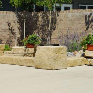 Outdoor garden area with stone benches and potted plants on a sunny day.