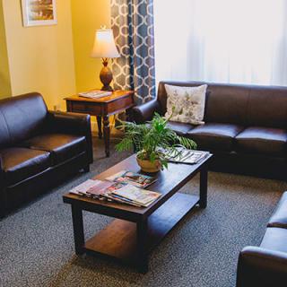 A cozy living room featuring leather sofas, a wooden coffee table with magazines, and a potted plant.