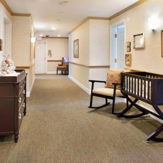 A well-lit hallway with carpeted flooring, decorated walls, and comfortable furniture.