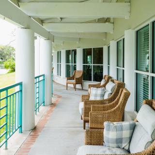 A peaceful veranda with wicker chairs and pillows, overlooking a green landscape.