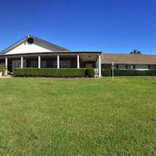 A charming rural house with a well-maintained lawn under a clear blue sky.