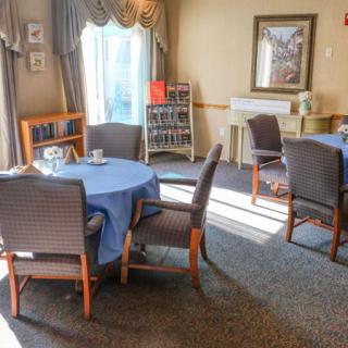 A cozy dining area with round tables covered in blue tablecloths and surrounded by cushioned chairs.