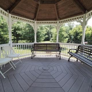 A serene gazebo surrounded by greenery, featuring multiple benches for relaxation.