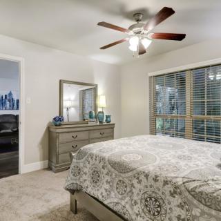 A cozy bedroom featuring a bed, dresser with a mirror, and a ceiling fan.