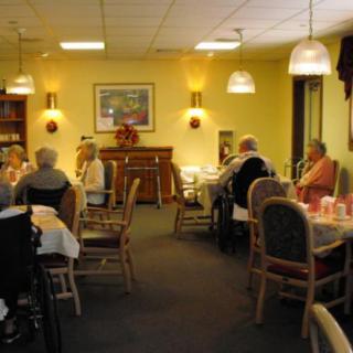 A cozy dining area with seniors seated at tables, enjoying a meal.