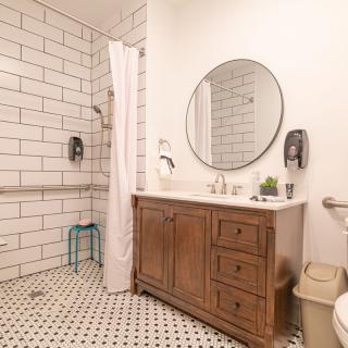 A modern bathroom with white subway tiles, a wooden vanity, and a round mirror.