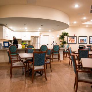 A cozy dining area with tables, chairs, and a view into the kitchen.