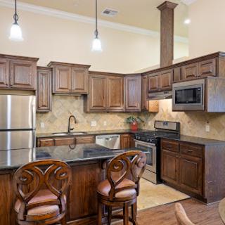 A stylish modern kitchen featuring wooden cabinets, stainless steel appliances, and a cozy seating area.