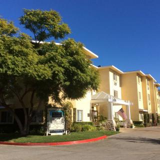 A sunny day view of a residential building with an entrance and surrounding trees.