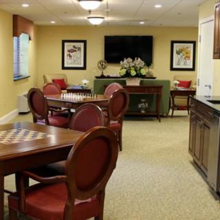 A cozy living room interior with wooden tables and chairs, a television, and decorative elements.