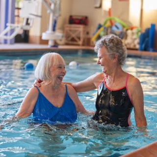 Two elderly women enjoying a joyful moment together in a swimming pool.