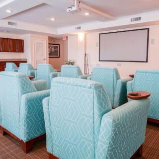 A small theater-style conference room with comfortable seating and a projector screen.