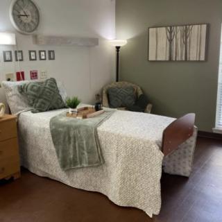 A cozy and well-decorated bedroom with a single bed, nightstand, lamp, and wall art.