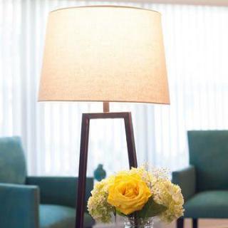 A cozy living room with a stylish lamp and a vase of yellow flowers.