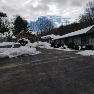 A snowy parking lot in front of buildings on a cloudy winter day.