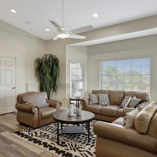 A cozy living room featuring leather sofas, a coffee table, and a large window allowing for natural light.