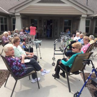 A group of elderly people sitting outside on a patio, enjoying each other's company.