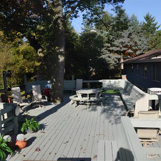 A spacious outdoor deck with furniture and surrounding greenery on a sunny day.