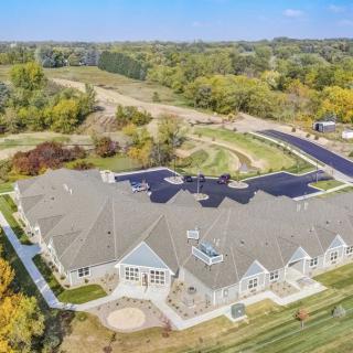 Aerial view of a large building surrounded by landscaped grounds and a parking lot in a rural area.