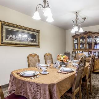A well-set dining room table with a chandelier and china cabinet in the background.