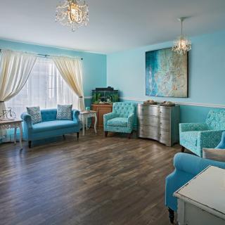 A modern living room with blue furniture and elegant chandeliers, filled with natural light.