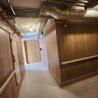 A well-lit hallway featuring wooden walls and various structural elements.