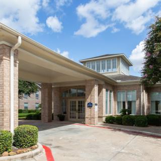The entrance of a hotel with a covered driveway and well-maintained landscaping.