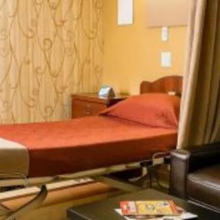 A cozy hospital room with a bed, side table, and comfortable furnishings.