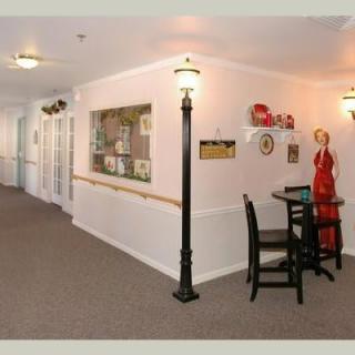 A warmly decorated hallway featuring artwork, furniture, and a floor lamp.