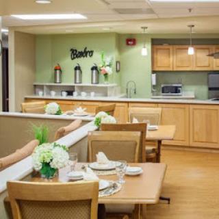 A cozy dining area with neatly arranged tables and a kitchen in the background.