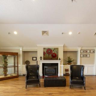 A spacious living room featuring a fireplace, two black chairs, and elegant decor.