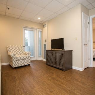 A cozy living room featuring a patterned armchair, modern TV stand, and warm wood flooring.