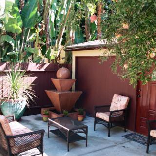 A cozy patio area with outdoor seating and a fountain surrounded by lush greenery.